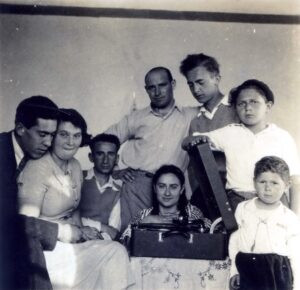 1935, הפטיפון הראשון במושבה הוא אטרקציה והאפשרות להאזין למוזיקה, מאחדת ומקרבת. מרדכי קסוינר הוא הנער חובש הכובע מימין, אחיו הצעיר יעקב מתחתיו (בבית הוריהם הפטיפון), יהושע טורנר במרכז וצבי השומר (מנצל את ההזדמנות לנסיונות לגיפופים עם הצעירה הנחמדה), משמאל.