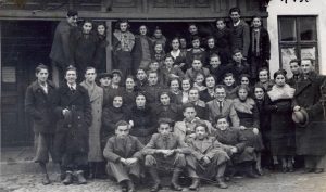 30 בנובמבר 1937 (על גב התמונה). בשלט שמשמאל ניתן לפענח "התאחדות - פועלי ציון", היא מפלגת האם של "גורדוניה". זוהי חזית בית המשרדים שלה ברחוב גולוחובסקי 13 בעיר, בו הוקצה מקום גם לפעילותה של "גורדוניה" וחצר בה פעלה מסגרית הכשרה לעולים ארצה - "הברזל". 
מזוהים רבים בתמונה, וביניהם: בשורה הארוכה במרכז, שמיני משמאל, הוא מוניו הלר. ככל הידוע, הלר חוסל ע"י הרוסים מיד עם כניסתם לעיר בספטמבר 1939. מנהיגים לאומיים (ציונים במקרה זה) פופולריים היו תמיד בראש רשימת החיסולים (או ההגליה לסיביר) שלהם, מרכיב חיוני ב"איסטרטגיית" הסיפוח הסובייטית בכלל. לצדו של הלר (שביעי משמאל) הוא אמסטר ששרד את תקופת המלחמה ונשאר לחיות בפולין לאחריה (אחיו, כנאמר קודם, עלה ארצה). בשורה מתחת, שניה משמאל, היא זושק'ה זיינפלד ששרדה אף היא ובארץ לאחר עלותה, בכפר מע"ש. יושב בחזית במרכז הוא גרייף שנהרג בתחנת הרכבת בעיר במהלך הנסיגה של הצבא הפולני בספטמבר 1939.