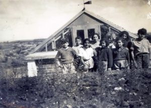 יולי 1936, בסיום כיתה ו', הילדים ליד מבנה החממה עם המורה (מנהלת המשק) פנינה בת יעקב (במרכז השורה האחורית). גדלו בחממה הזאת ירקות לא שגרתיים וגם שלא בעונתם ! הילדה דבורה שריאן (כותבת הברכה על גב התמונה), בשורה הקדמית שניה מימין.