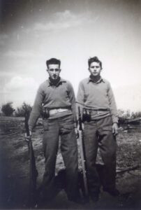 כיתוב על גב התמונה: "כפר יעבץ, 12 בפברואר 1948". 
יום טוב, משמאל, ושמוליק אבן טוב חגורים פאוצ' ובו שני רימונים. הפאוצ' הפרימיטיבי היה עשוי בד וכונה "בנדולרה". הרובים הם רובים אנגלים מסוג "מארק 4" ו "מארק 5".