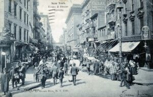 שנה לאחר מכן (1906) באותה נקודה בדיוק, צומת הרחובות הסטר ואסקס (Essex), הוא האזור בו הוקמו באותן שנים בתי המגורים עצומי-המידות (Tenements), בכמה מהם ניתן להבחין בתמונות כאן, אשר אכלסו בדירות קטנות, בתנאי דוחק וצפיפות, את גלי המהגרים (יהודים במקרה זה) אשר נהרו לארה"ב בחיפוש אחר עתיד טוב יותר.