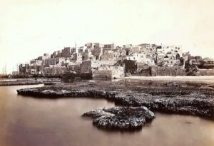 1870 בקרוב, נמל יפו בצילום מפואר של האיטלקי ג'אקומו ברוג'י (Giacomo Brogi). כמו בן זמנו המפורסם, פליקס בונפיס, ברוג'י (1822-1881), היה מהצלמים הארופאים הראשונים שצילמו בלבאנט (למסעו הראשון הוא יצא ב 1868). 
החומה הדרומית הכפולה בימין התמונה, והחפיר בתווך, נראית שלמה לחלוטין במועד הזה. בשטח ההפקר שבין החומות ניטעו "כרי גינה בין שתי החומות" (בערבית: "גניינה בין סוריין") שהתושבים יכלו לעבד. גוש הבנינים התחום בין החומה לקו המגדלור (כולל) הוא שכונת טאבייה (Tabyeh) הקטנה. בקצה הימני העליון של התמונה, בית המידות המפואר בעל הקשתות הוא בית הקונסול סלים קסאר, המבנה שידוע כיום כמוזיאון אילנה גור. בעקבות התפתחותה המואצת של העיר ואיתה תחילת הבניה מחוץ לחומות בחצי השני של המאה ה 19, איבדה החומה בעקביות את משמעותה ובשנת 1888 נהרסו שרידיה האחרונים.