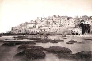 1870 בקרוב, צידו הצפוני של הנמל בתצלום מרהיב של פליקס בונפיס (Felix Bonfils), בונפיס הצרפתי (1831-1885), מגדולי צלמיה של ארץ ישראל והלבנט, לאחר מותו המשיך בנו אדריאן את מפעלו. 
בימין התמונה ניתן להבחין במגדלור ההנחיה לספינות (הוקם ב 1865 ע"י חברה צרפתית שהיתה בעלת זיכיון מטעם האימפריה העות'מנית לבניית מגדלורים בחופי הים התיכון והים האגאי). אפשר להתרשם גם עד כמה קדמת הנמל היתה זרועה ומוקפת בסלעי השונית. מספר שנים מאוחר יותר, ב 1875, הרחיבו השלטונות את המעבר אל המעגן (במקור היה רוחבו אך כחמישה מטרים !) ע"י פיצוץ הסלעים שבצידיו.