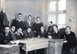 יוני 1946, ההנהגה הראשית של "איחוד הנוער הציוני ועקיבא" בפולין, לודז', רח' זוודזקה 12 דירה 31. בספרו "עוברים כל גבול", בעמ' 311, כותב יוחנן כהן (יושב שני מימין) על מעמד זה בדיוק. כהן, איש "הנוער הציוני", בן העיר לודז', ממקימי קבוץ תל יצחק, לאחר השואה נשלח לפולין כדי לחזק את שורות "הבריחה" וכאן עם רעיו לתנועה (חלקם גם חברי "הבריחה") אשר את תקופת המלחמה והשואה עברו בארופה. 
במכתב הדרמטי הנספח כאן נוכל להתרשם, ממקור ראשון, בטיב העבודה הנעלה שהללו לוקחים בה חלק באותם ימים ממש !