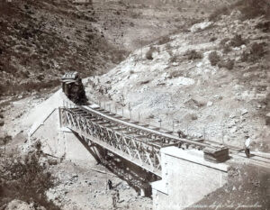 הרכבת מיפו לירושלים, תצלום של האחים קונסטנטין וג'ורג' זנגאקי (Zangaki). אף שהתצלום אינו חתום, דרך הכיתוב בתחתית התמונה בצרפתית - "הנחת מסילת הברזל לירושלים" וצורת המספור - 1110 במקרה זה, הינם באופן מובהק חזותית מסימני ההיכר שלהם. 
התוואי ההררי, הפועלים הרבים הנראים מכל עבר והמעמד הסמלי לכאורה, מצביעים על כך שהתצלום נעשה בזמן עבודות אחרונות ונסיעות מבחן לקראת פתיחתו הרשמית של הקו ב 26 בספטמבר 1892. המסילה לירושלים, זאת יש לזכור, הקדימה בעשור ויותר את סלילת קו רכבת החיג'אז ואת שלוחתו הצנועה, "רכבת העמק".