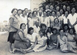 חנה מייזל (ממושקפת) במרכז מוקפת בתלמידותיה. כורע לצידה של מייזל (קירח), המורה לשתלנות שלמה ויינברג (אורן), עומד לימינה, המורה אלימלך לוין מנהלל, מומחה בתחום גידול העופות. עוד בשורת העומדים החזיתית, התלמידה השניה מימין היא בתיה ויינברג ממושבת האורגים ג'דה הסמוכה לנהלל. את מרבית המורים הראשונים לביה"ס גייסה מייזל מקרב חבריה לדרך, קבוצת החלוצים מייסדי המושב נהלל. עוד על ראשוני המורים ראו בנספח.