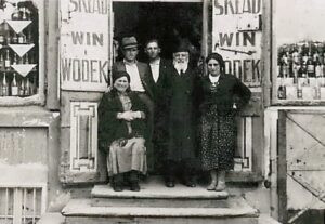 בית ממכר (Sklad בפולנית) אופייני למשקאות אלכוהוליים ("וודקה ויין" בשילוט שבפתח) בגליציה. אף שהמשפחה שבבעלותה המקום אנונימית מבחינתנו, מפתיע הדימיון הרב בחזותם ובלבושם לבני הזוג רוזנקרנץ, ילדיהם וכלותיהם !