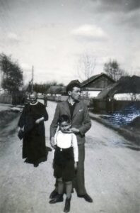 על רקע רחוב נאה אופייני של הכפר/העיירה היהודית, איטה רוזנקרנץ מאחור, נכדה (בן בנה הבכור מקס) ובנה ברוך (בוצ'ו), דודו של הילד, בחזית. שלושת המצולמים נספו בשואה.