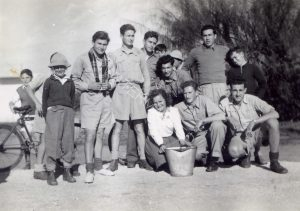 כיתוב: כפר הס, 8.1.1948
בזמן שהות של שבועיים בכפר, התגוררו במועדון. כאן עם ילדי הישוב. למטה מימין: מוטולה, דוברי. למעלה מימין: ליפא בנימיני (נפצע מרסיס פגז בקרב לטרון), אברמל'ה אנגלנדר, שמוליק אבן טוב, לא זכור בשמו, משה שומסקי.
