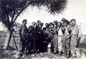 קולה. יצחק וייס (ויס) מציץ שני מימין וחברים
סיפורו הטרגי של ניצול השואה יצחק ויס שנהרג במהלך סיור רגלי ממגדל צדק לראש העין ב 21.8.48, כחדש ימים לאחר ארועי תמונה זו, מפורט בנפרד בתעוד סיפורי נופלים. ויס עלה על מוקש או הפעיל מטען צד ונהרג במקום. שני משמאל החובש אלי (בונדי) פרסר, חברו הטוב של ויס מרומניה.