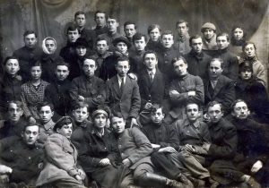 טקסט ביידיש, במקור לצד התמונה, מבאר במה הדברים אמורים: "קבוצת החלוצים הראשונה מאוקראינה, 1919, ההנהלה הראשית עם החבר רובינשטיין מוורשה". 
הקרבות של שלהי מלחמת העולם הראשונה, הפרעות הקשות ביהודי המרחב הזה בעקבות מלחמת האזרחים האוקראינית בשלהי מלחמת העולם ומיד לאחריה ("פרעות פטלורה"), וכלה במלחמה בין רוסיה הבולשביקית לפולין שפרצה באביב 1920, בכל אלה היו היהודים לשק החבטות של הצדדים הניצים. רישומיהן הקשים בזיכרון הלאומי - קטל של מאות אלפים וחורבן טוטלי של קהילות שלמות - הוקהו במידה רבה עם בוא השואה שגימדה אותן. לצד רובינשטיין במרכז (השורה השניה מלמטה), הפעילים הרובנאיים שעסקו במפעל האדיר הזה של סעד לפליטים - פ.ל. הירשפלד (רביעי משמאל) ושמואל רוזנהק וישראל דינס (שישי ושביעי משמאל בהתאמה).