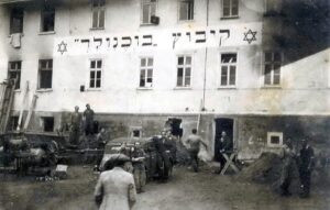 בחודשים האחרונים של 1945, שלבי התארגנות בביתו החדש של הקיבוץ בגרינסהוף. עגלת עץ גדולה (הנרתמת לסוסים) בשמאל התמונה, ציוד עבודה וציוד בניה מפוזרים בשטח. תמונה המשדרת עוצמה ללא ספק.