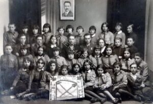 אפריל 1931, חברי תנועת הנוער "פרייהייט" עם ראש הקבוצה לייבל צוקרמן, במרכז, בתמונת מזכרת לרגל הוועידה הארצית השניה של התנועה שהתקיימה בוורשה. מזוהה גם מורה הגמנסיה "תרבות", מנחם גלרטר, שני משמאל בשורת המבוגרים. דגל "האת והפטיש" בידי החניכים בחזית, והכיתוב בו: פרייהייט (= חרות), יידישע סאציאליסטישע ארבעטער יוגנט פון פוילען (= נוער יהודי סוציאליסטי עובד, בפולין). תמונת דב בער בורוכוב תלויה על הקיר מאחור. עוד ובהרחבה אודות סניף התנועה ברובנה, ראו בנספח.